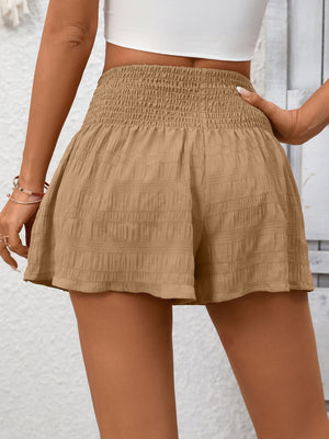 Khaki smocked waist drawstring shorts with textured fabric and a flared hem.
