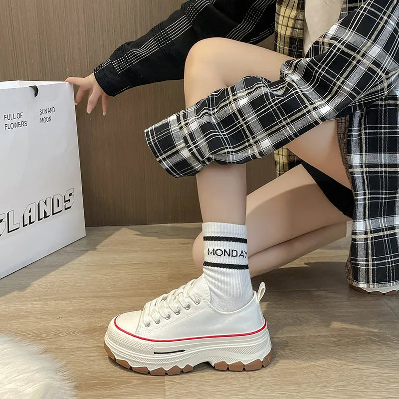 White canvas tread sneakers with red trim and chunky sole.