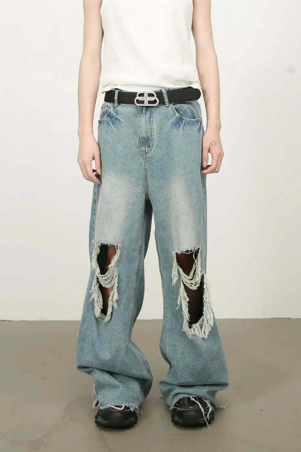 Distressed wide-leg denim jeans in medium wash with fraying and ripped details.