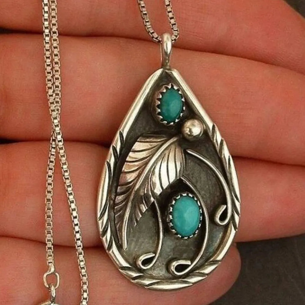 Silver pendant with turquoise stones and feather detail on a chain