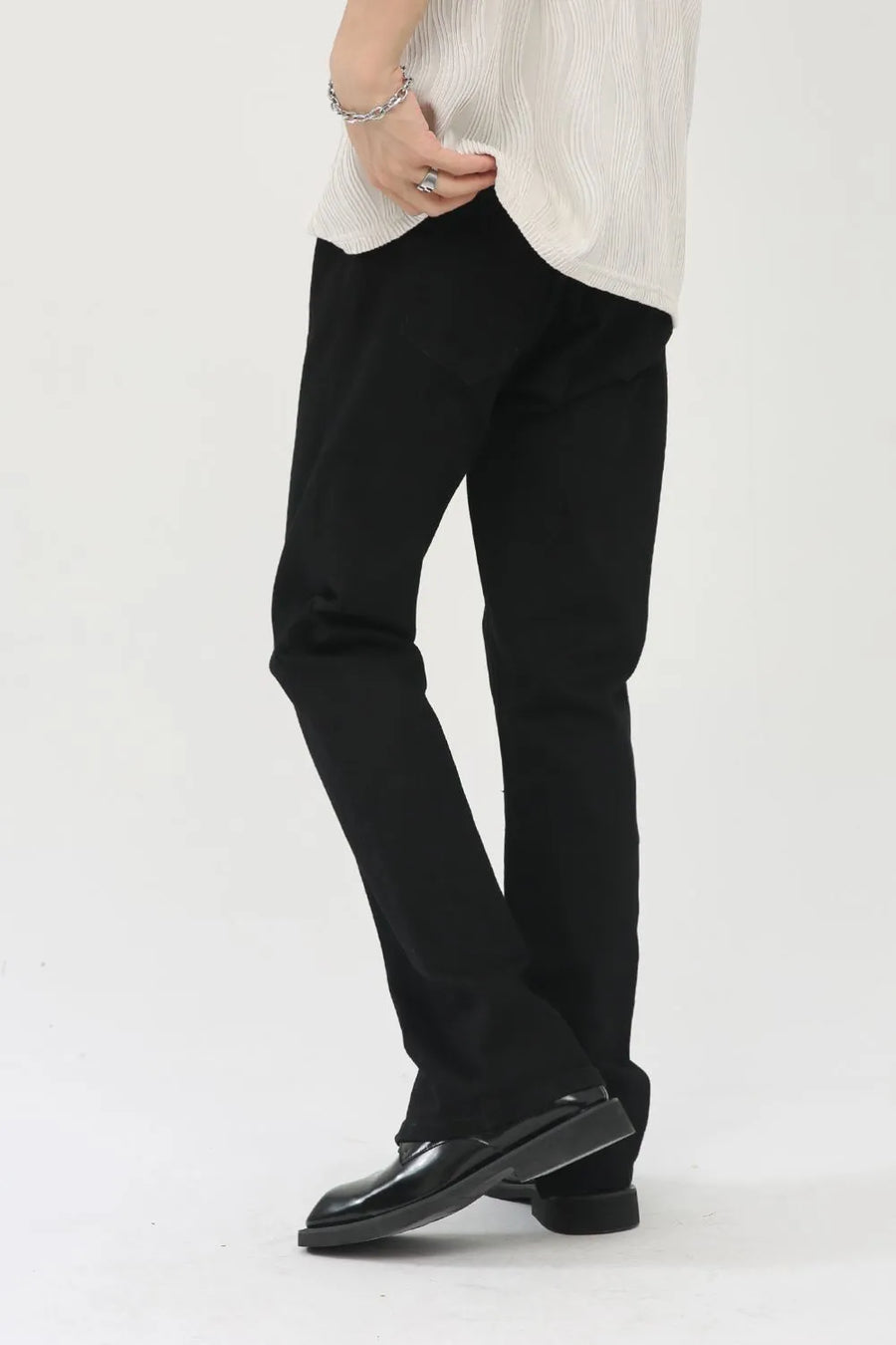Black denim trousers with zip hem detail, styled casually.
