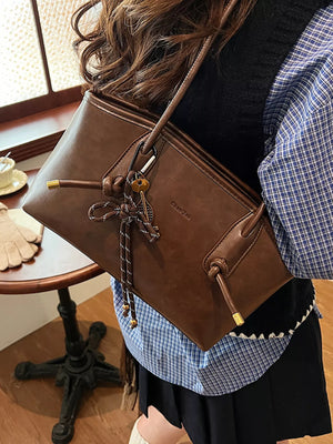 Brown leather shoulder bag with drawstring detail and gold hardware.