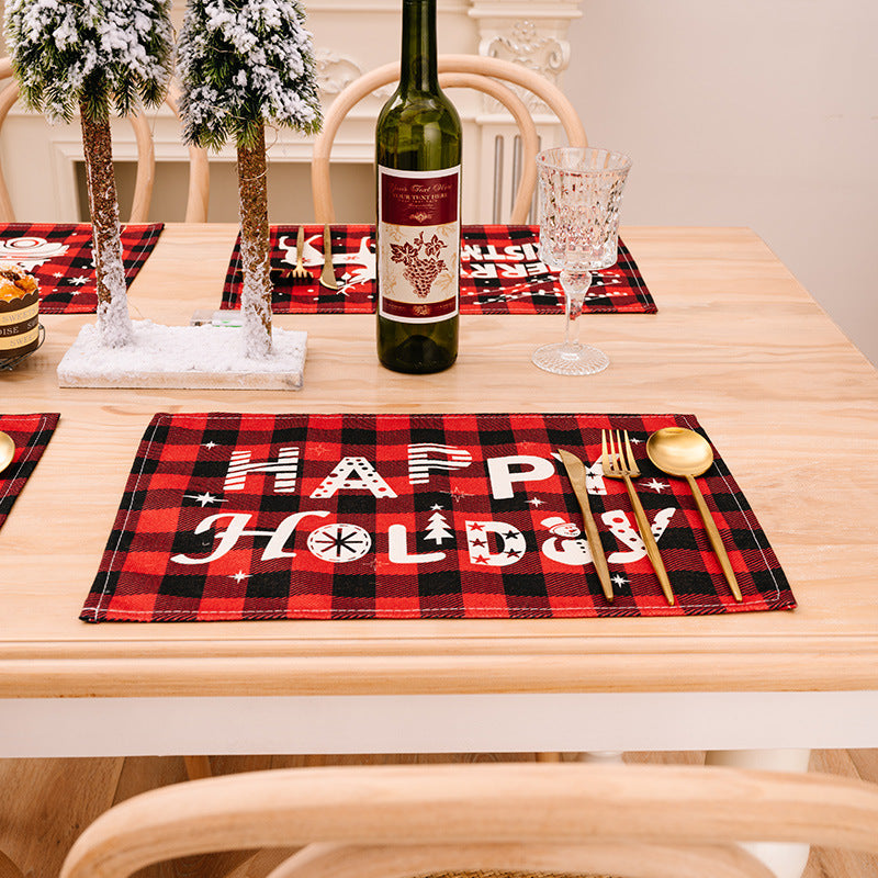 Festive plaid placemat with Happy Holiday text and Christmas icons in red and black.