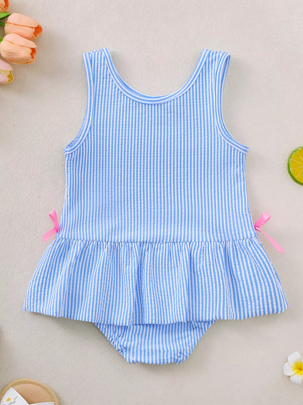 Blue striped seersucker one-piece swimsuit with ruffled hem and pink side bows