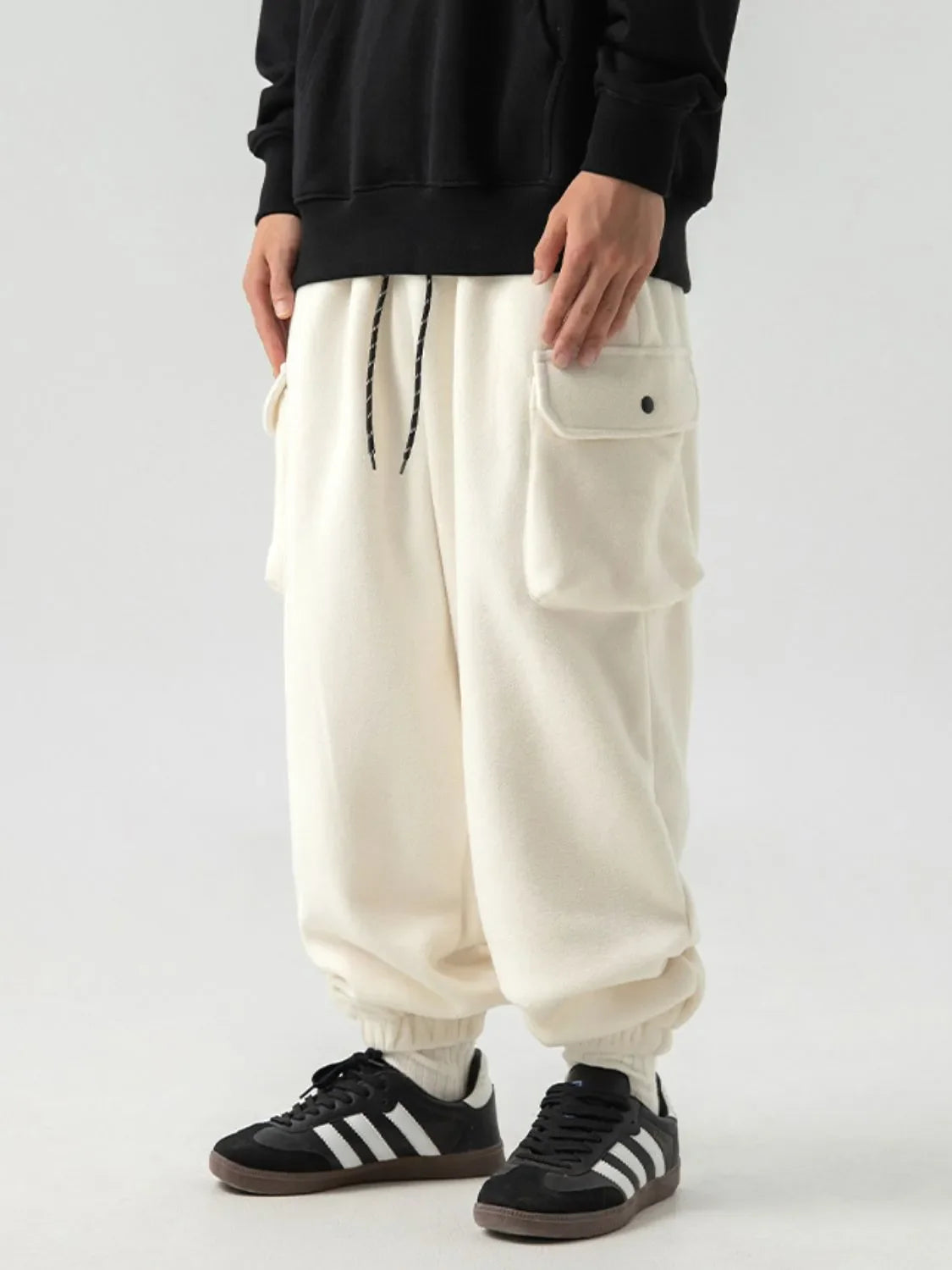 Ivory fleece cargo joggers with drawstring and button flap pockets.