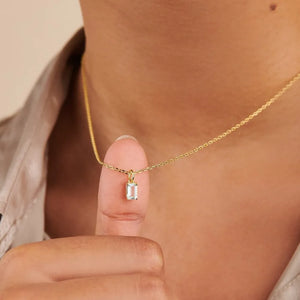 18K gold necklace with a rectangular prism cut gemstone pendant.