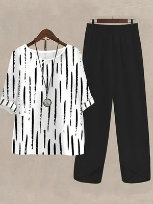 White half sleeve top with black vertical brushstroke print and black pants.