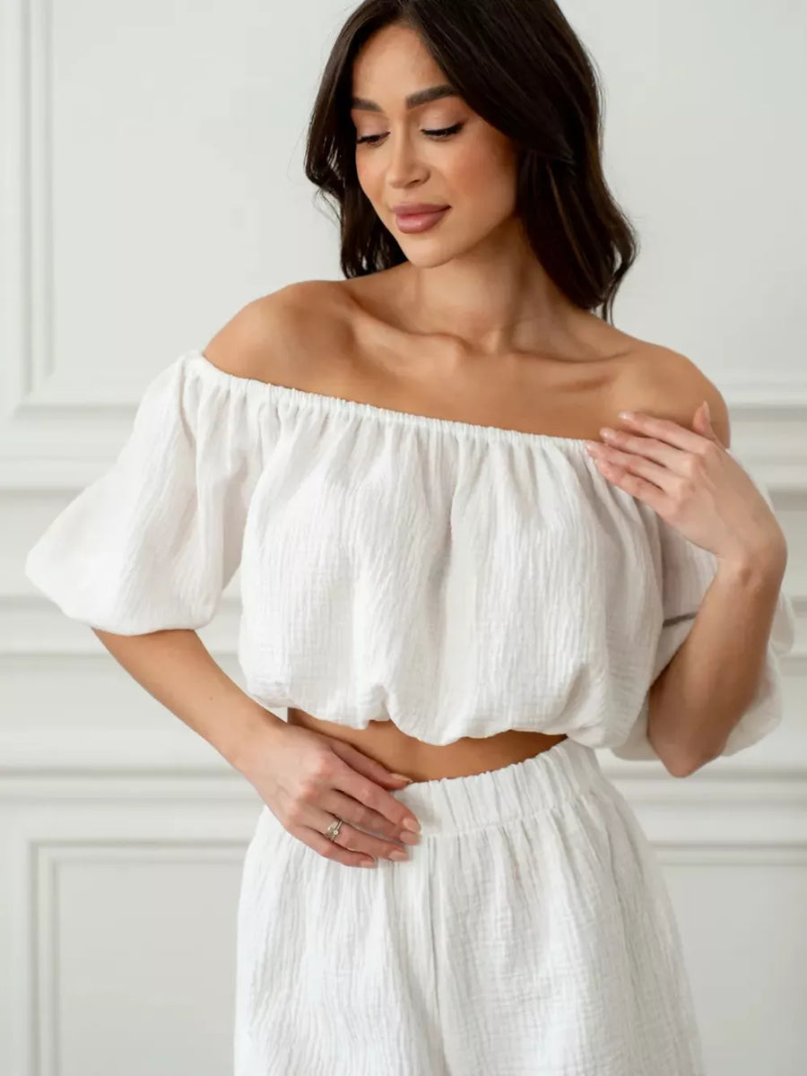 White off-shoulder cropped top and shorts set in textured cotton, featuring puff sleeves and elastic waist.