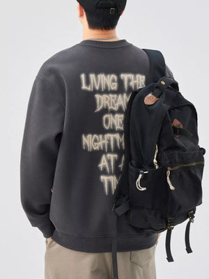 Oversized dark gray crew-neck sweatshirt with distressed graphic text on back.