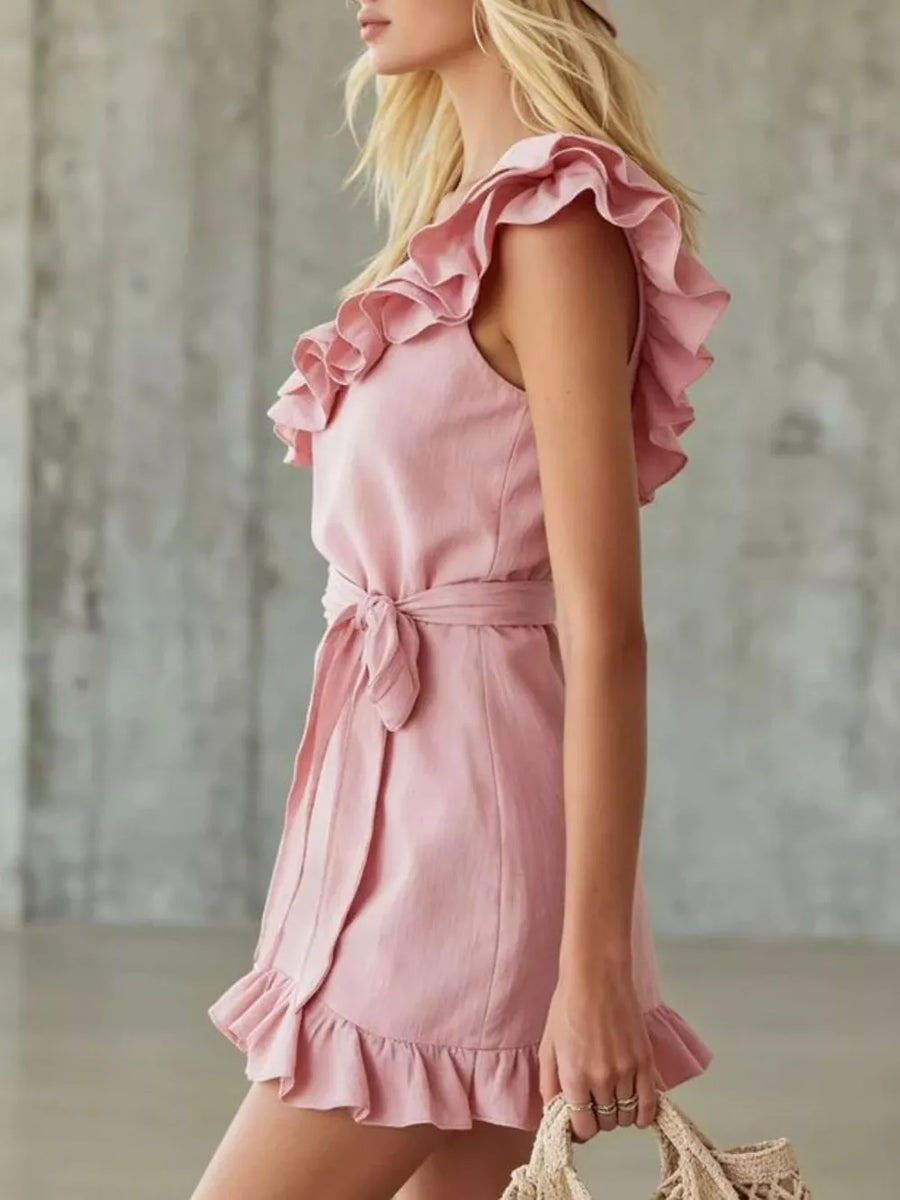 Blush pink wrap dress with ruffle trim on neckline and hem, and a tie waist.