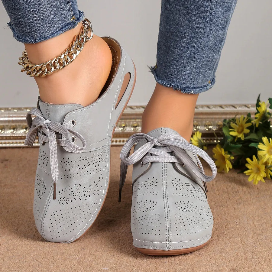 Gray perforated lace-up mule flats with cut-out sides and tie closure.