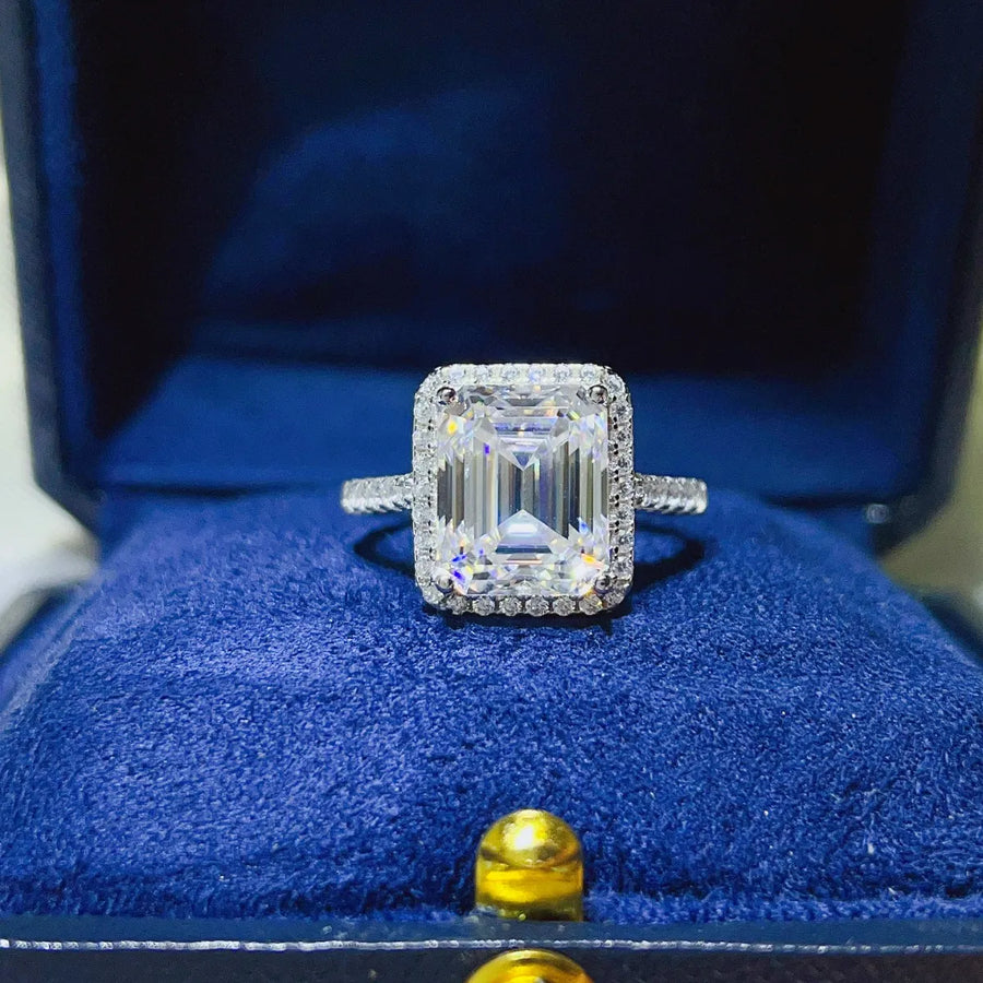 Emerald cut moissanite halo ring in sterling silver with pavé band.