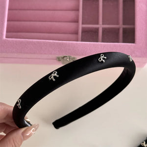 Black satin padded headband with silver bow embellishments