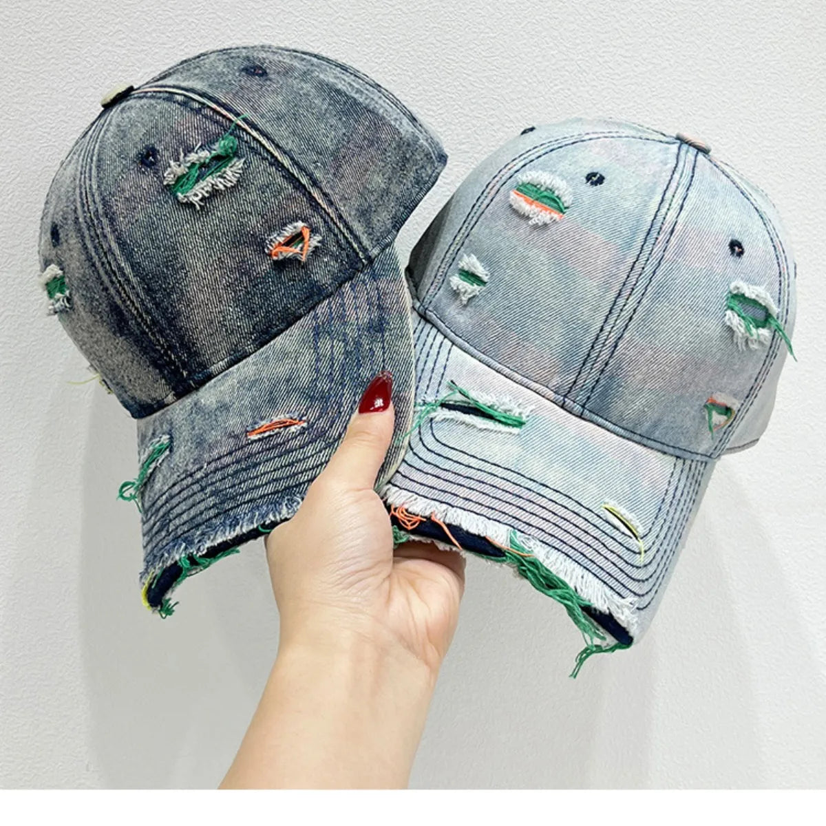 Distressed denim baseball cap with fraying and colorful stitching detail.