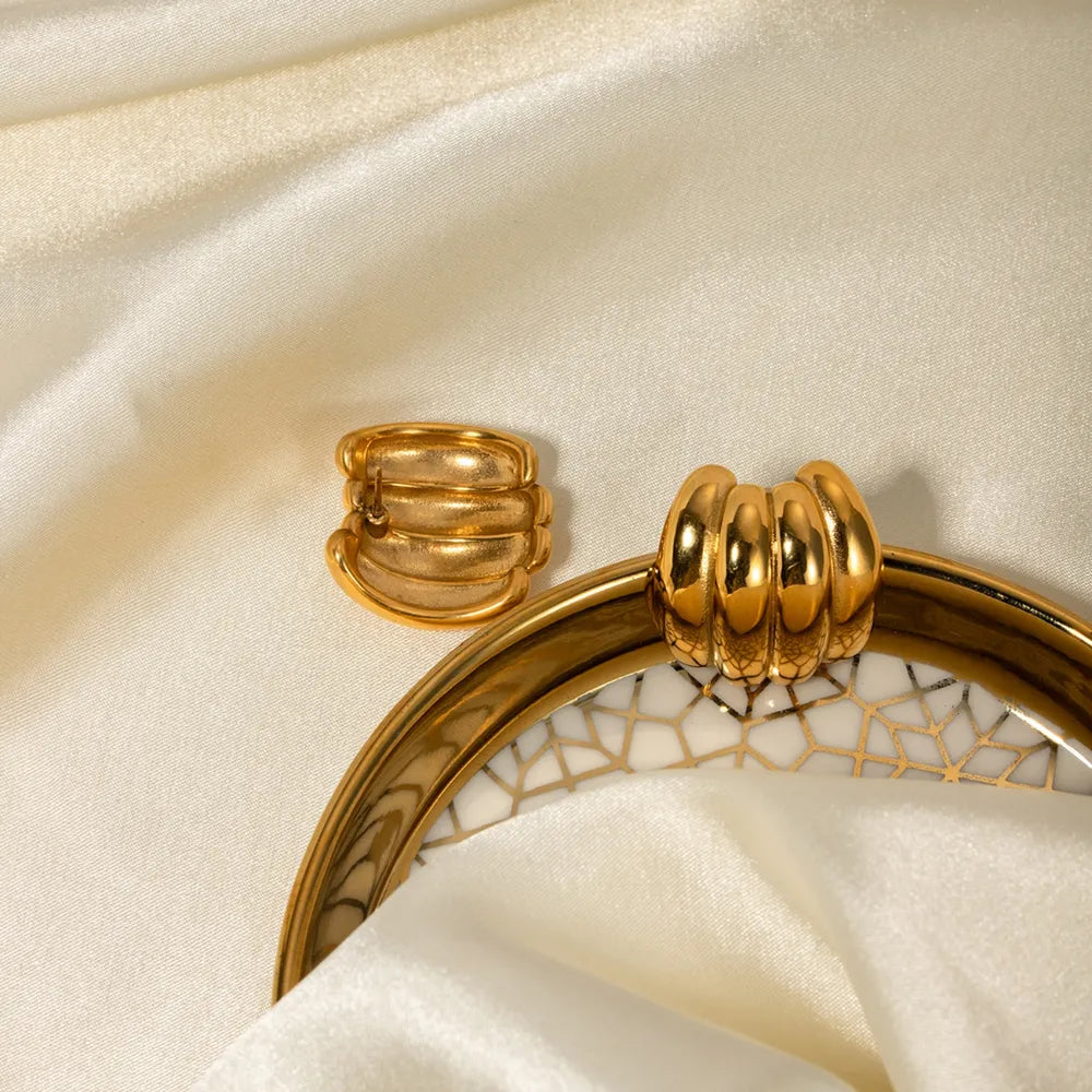 Sculptural ribbed gold hoop earrings with a textured finish, 18K gold-plated.
