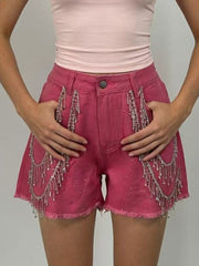 Fuchsia pink denim shorts with rhinestone embellishments and chain fringe detail.