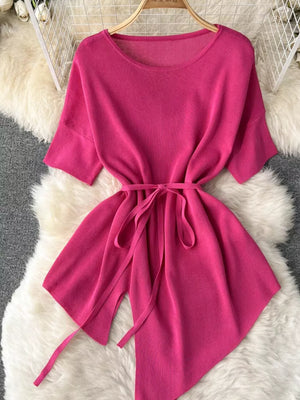 Pink tied waist knit top with asymmetric hem and wide sleeves.