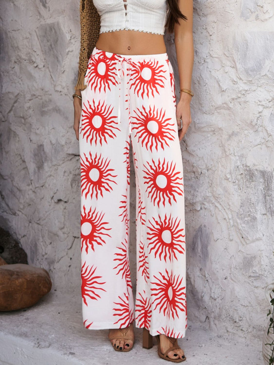 Geometric print wide-leg drawstring trousers in white with red sun pattern.