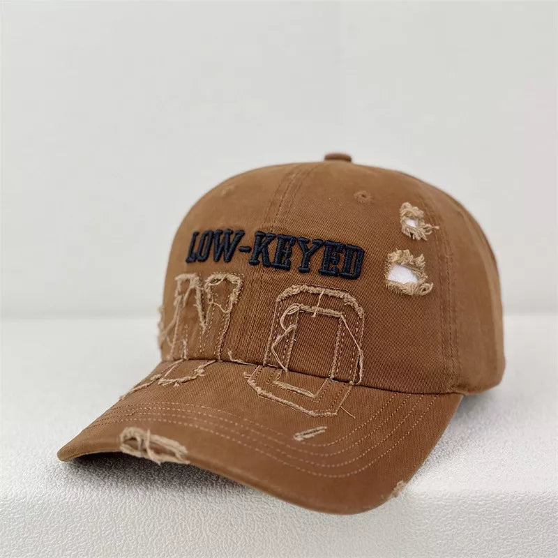Brown distressed baseball cap with embroidered text and frayed details.