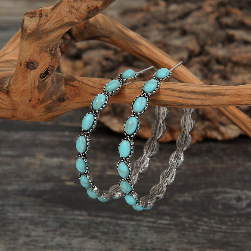 Teal stone hoop earrings with silver twisted metal detail and oval turquoise stones.
