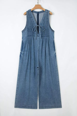 Denim jumpsuit with V-neck, tie detail, pintuck bodice, sleeveless, and wide legs.
