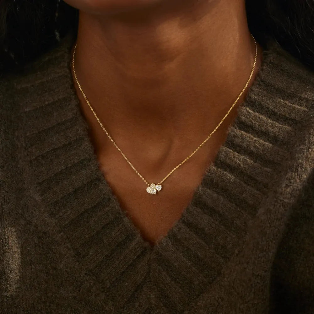 Gold chain necklace with two small heart zirconia charms.