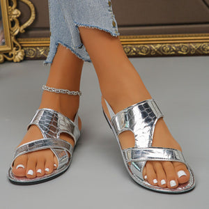 Silver crocodile-embossed open-toe sandals with criss-cross straps and a slingback.