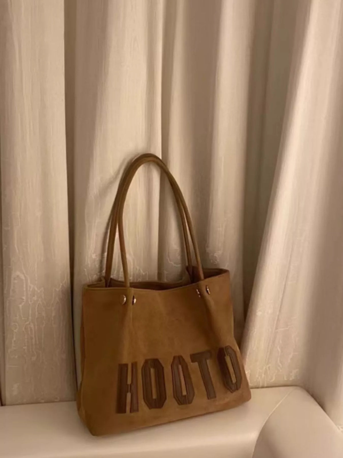 Brown PU leather tote bag with embossed lettering and double straps.