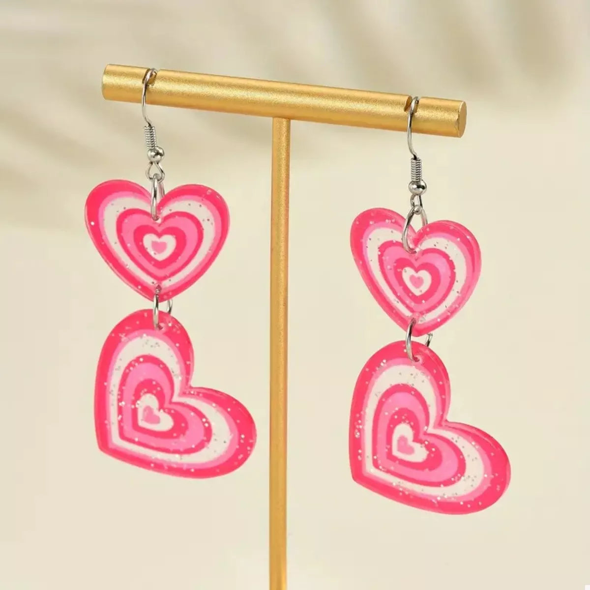 Pink layered heart dangle earrings with glitter accents