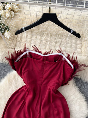 Wine red strapless jumpsuit with feather trim and wide legs.