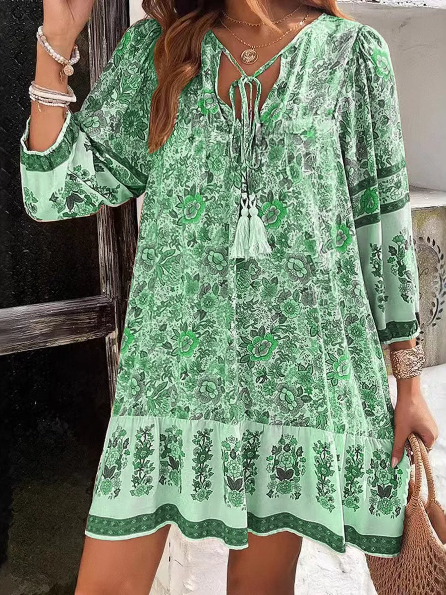 Vibrant floral print mini dress in Matcha Green with tassel tie neckline and tiered hem.