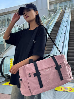 Pink duffel bag with black straps and adjustable shoulder strap.