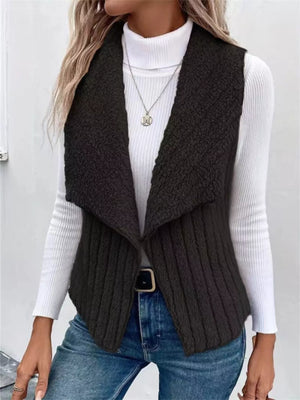 Black open front fleece vest with ribbed texture and shawl collar, styled with a turtleneck and jeans.