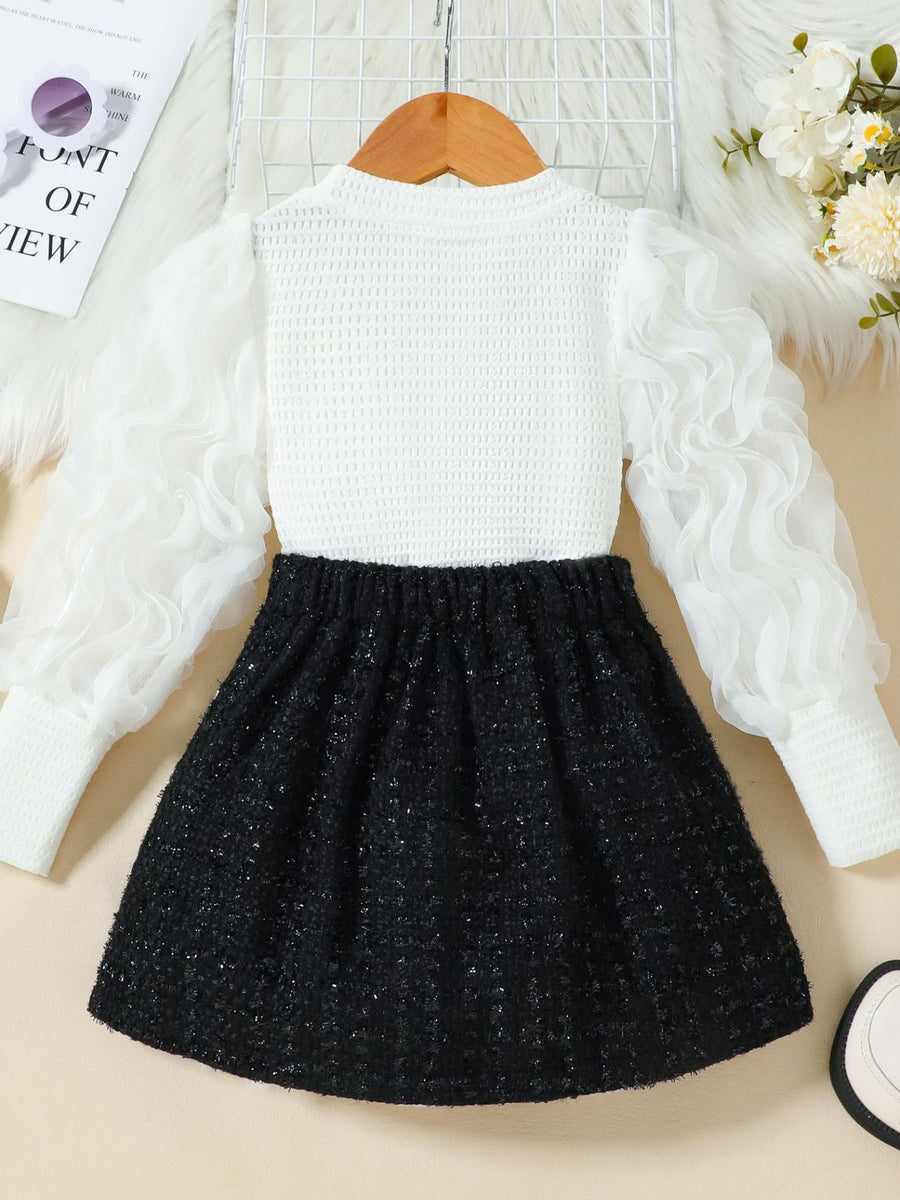 Children's white textured top with sheer ruffled sleeves and black tweed skirt.