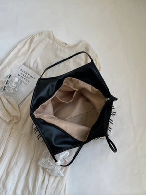 Beige shopper bag with black stripes and a lace bow detail, open to show interior.