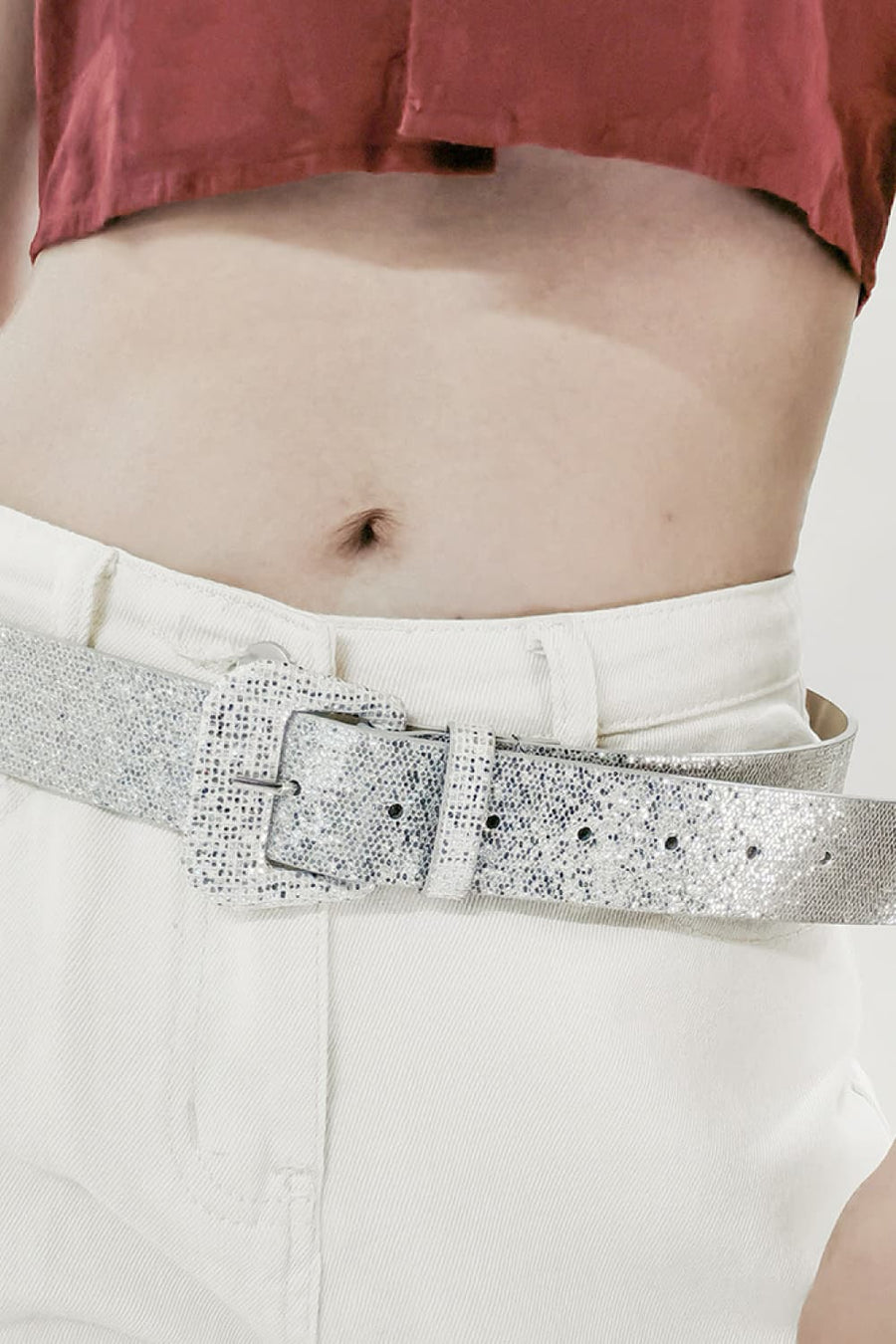 Silver glitter belt with a square buckle, worn with white jeans.