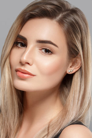 Ascending moissanite cluster stud earrings in gold with three sparkling stones.
