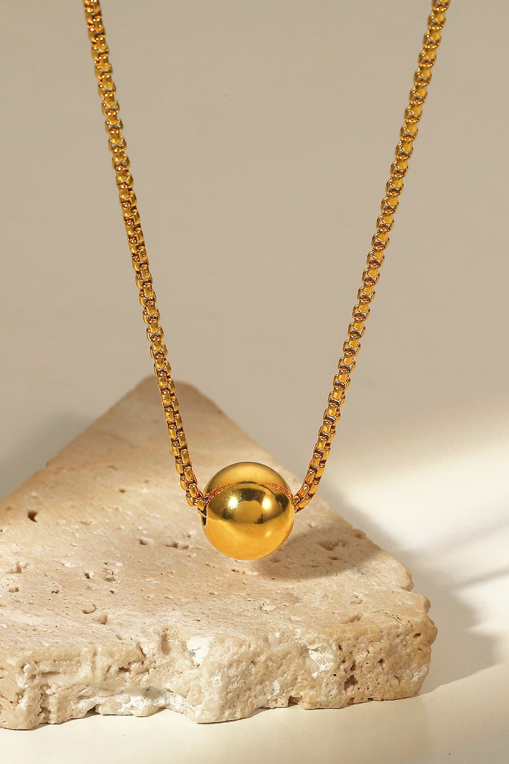 Gold orb pendant necklace with a box chain.