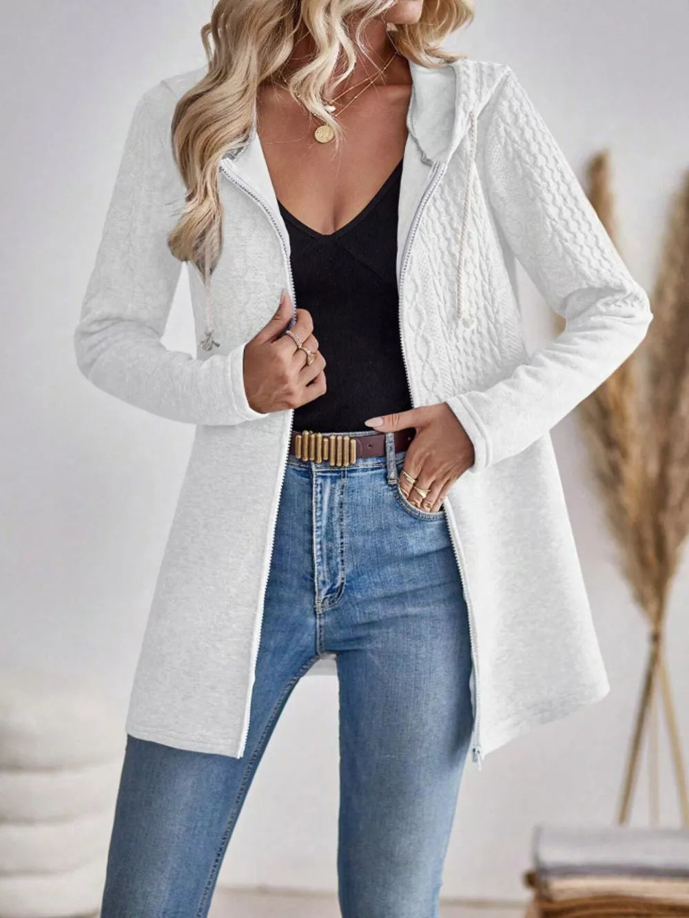 Ivory cable-knit hooded zip jacket with textured sleeves and front zipper closure.