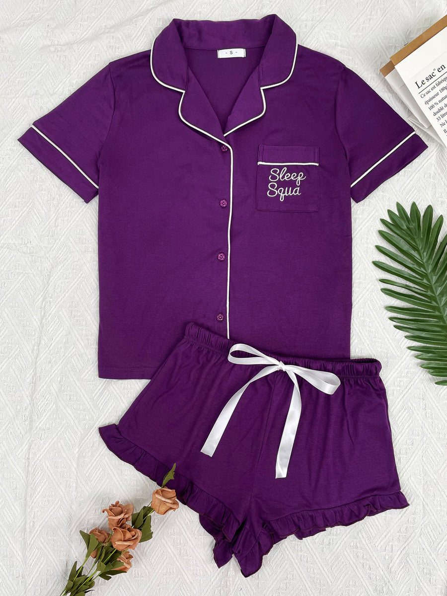 Purple pajama set with white trim, pocket embroidery, and ruffled shorts