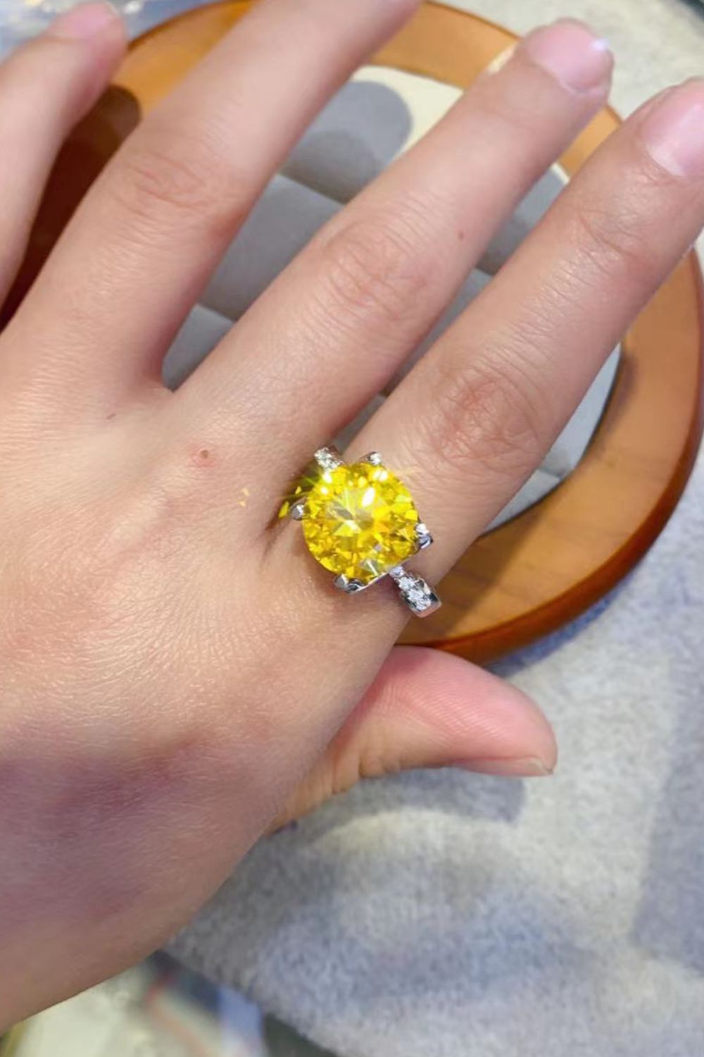 Silver solitaire ring with a bright yellow canary diamond and small accent stones.