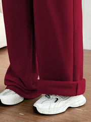 Burgundy wide-leg maternity joggers with cuffed hems, styled with white sneakers.