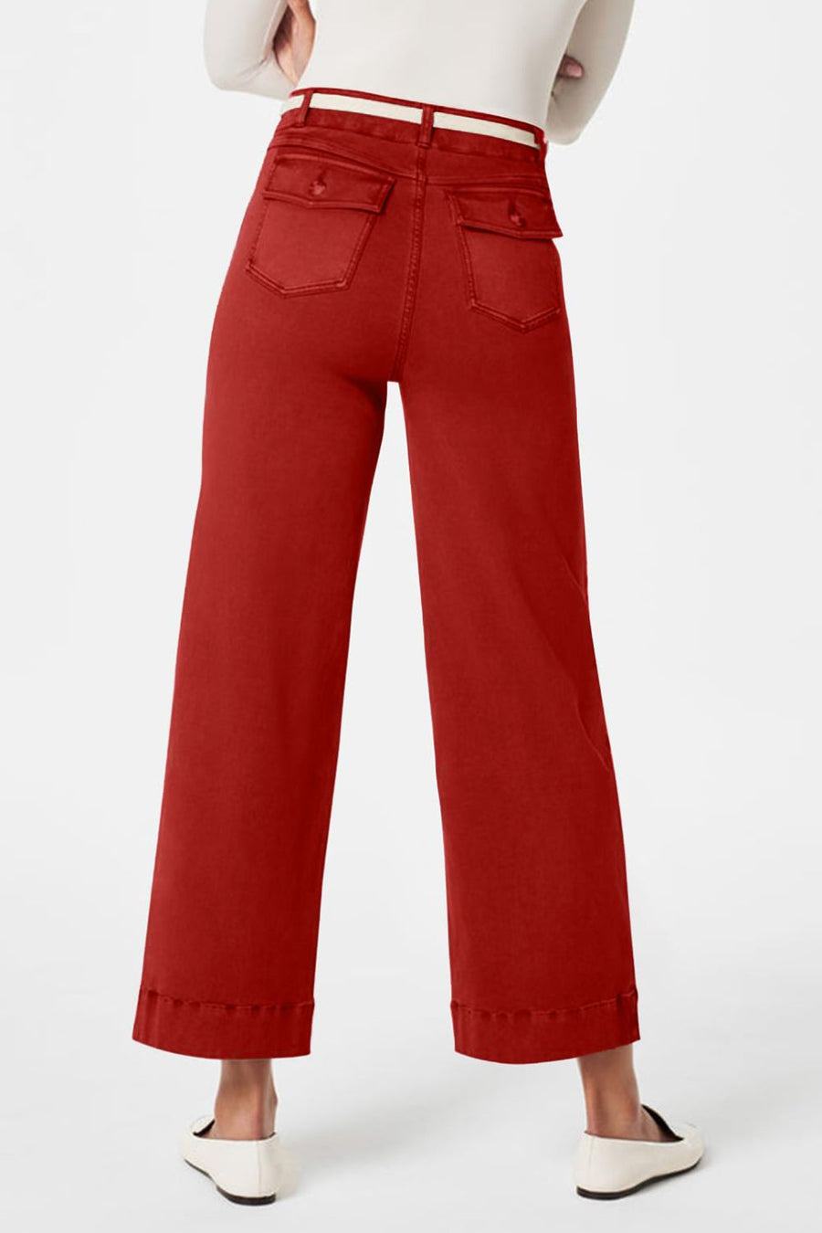 Wide-leg utility denim trousers in rust with buttoned back pockets and a white belt.
