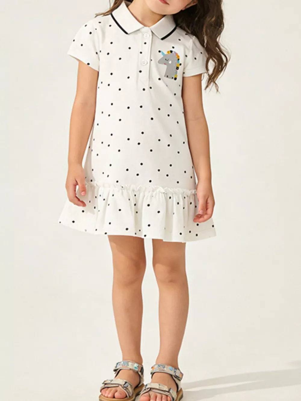 White polka dot cotton dress with unicorn patch and ruffled hem.