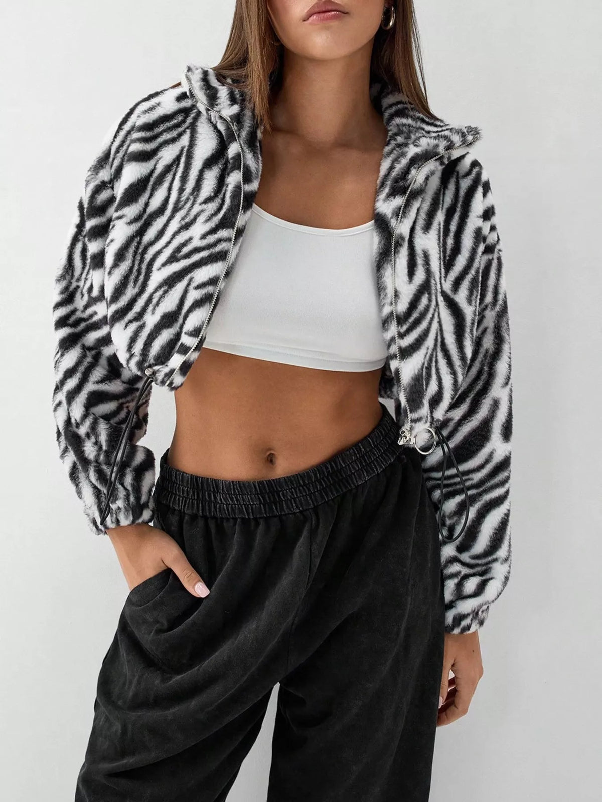 Plush cropped zebra print jacket in black with drawstring closure and zip front.