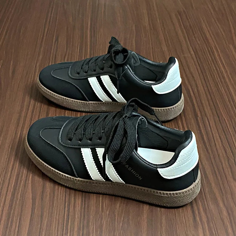 Black leather sneakers with white stripes and branding detail.