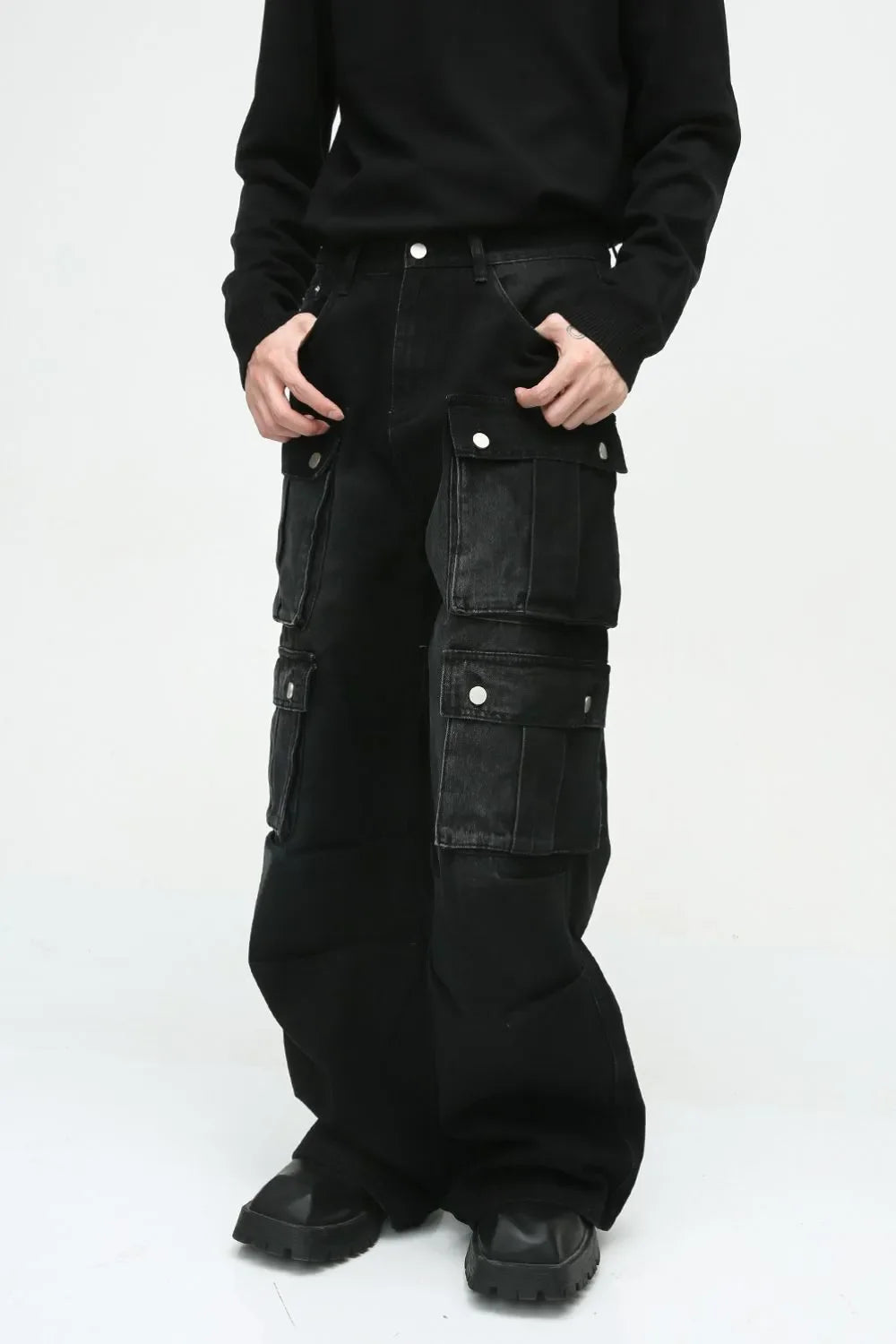 Dark cotton wide-leg cargo pants with multiple utility pockets and silver snap closures.