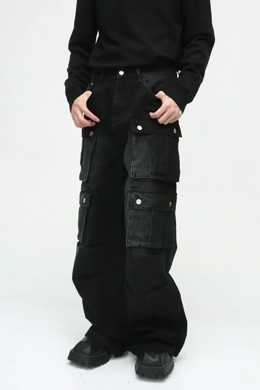 Dark cotton wide-leg cargo pants with multiple utility pockets and silver snap closures.