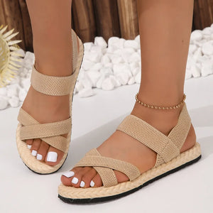 Beige woven sole crossover sandals with elastic straps and a braided espadrille sole.