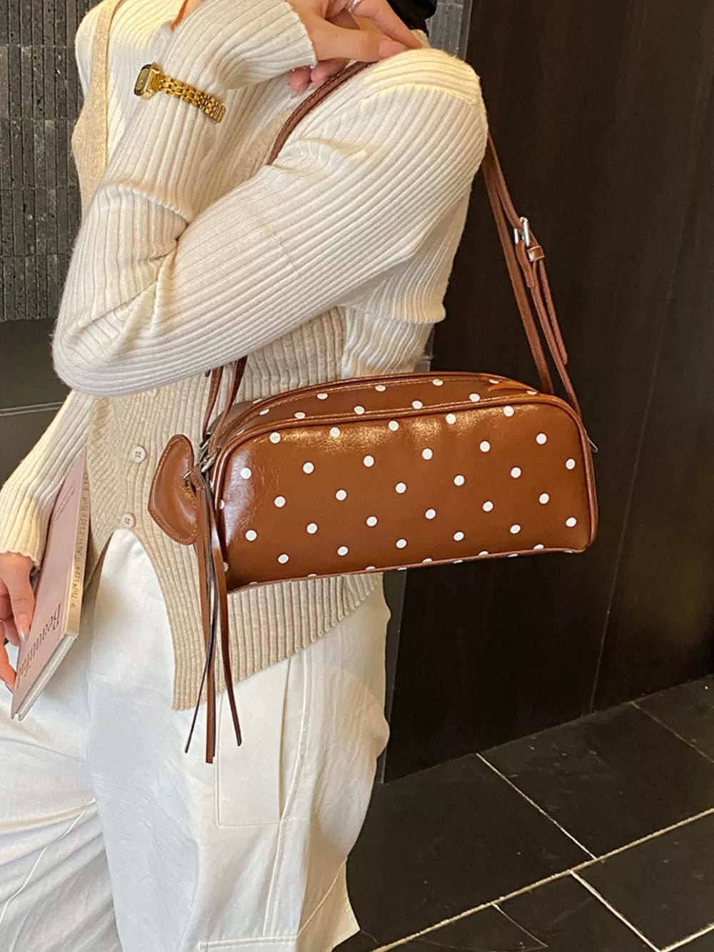 Brown polka dot shoulder bag with adjustable strap and tassel detail
